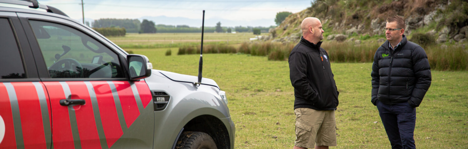 WK advisor speaking with a rural business owner beside a branded vehicle on farmland, discussing business strategy and financial advice.