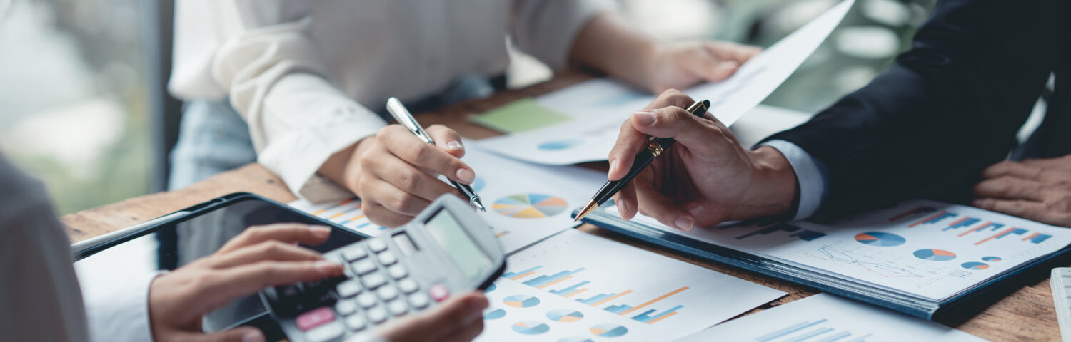 Business professionals reviewing financial charts and calculations during a meeting.